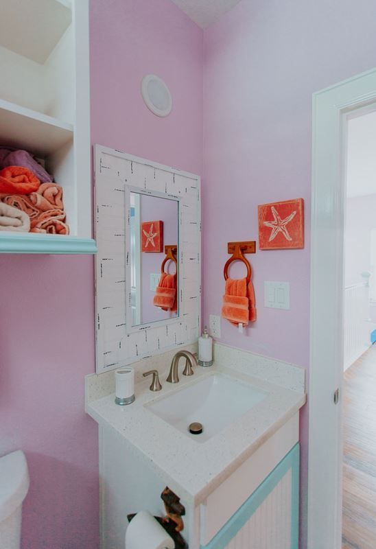 A bathroom with pink walls and a sink and mirror