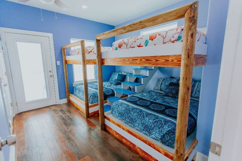 A bedroom with three bunk beds and blue walls.