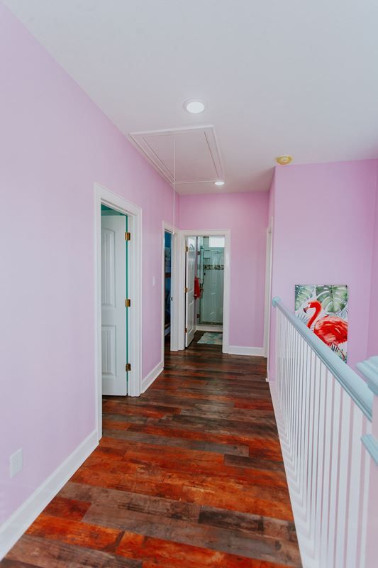 A hallway with pink walls and wooden floors in a house.