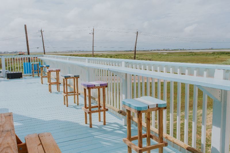 A deck with tables and stools and a view of a field.