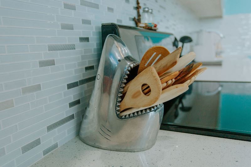 A shark shaped utensil holder filled with wooden utensils on a kitchen counter.