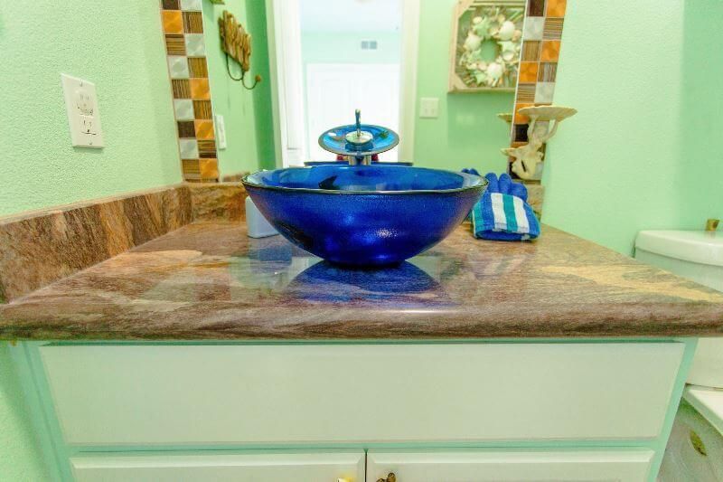 A blue glass sink is sitting on top of a bathroom counter.