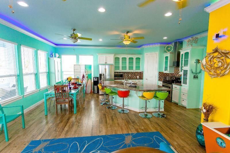 A living room filled with furniture and a kitchen with a ceiling fan.
