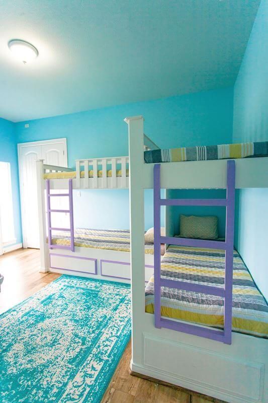 A bedroom with two bunk beds and a blue rug.