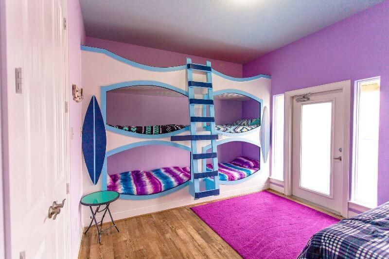 A bedroom with purple walls and a bunk bed with a ladder.