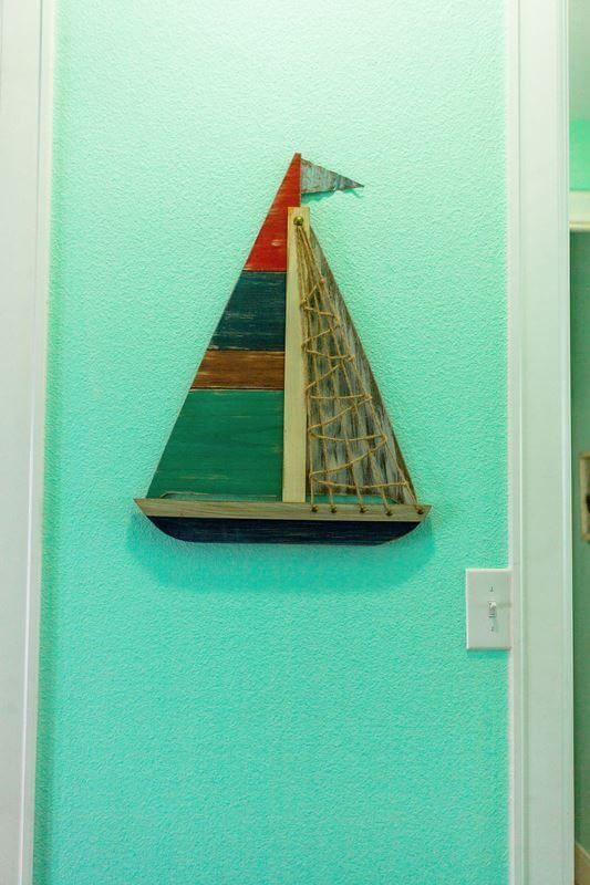 A model sailboat is hanging on a blue wall.