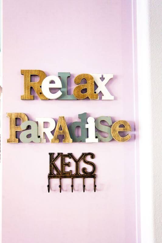 A sign that says relax paradise keys on a pink wall