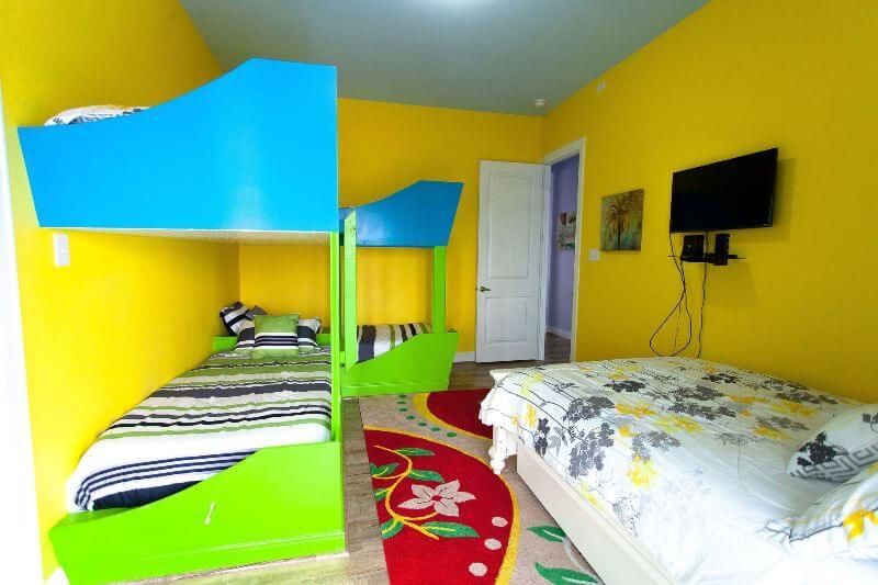 A bedroom with bunk beds and a television on the wall.