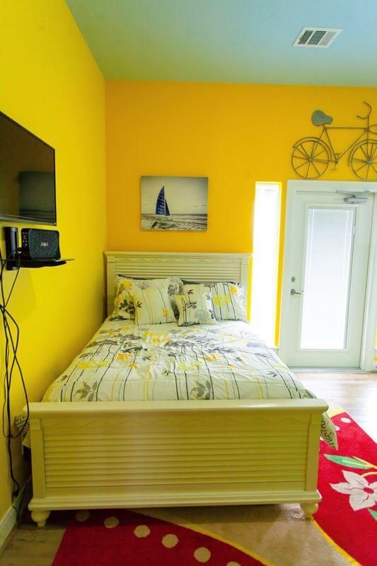 A bedroom with yellow walls and a white bed