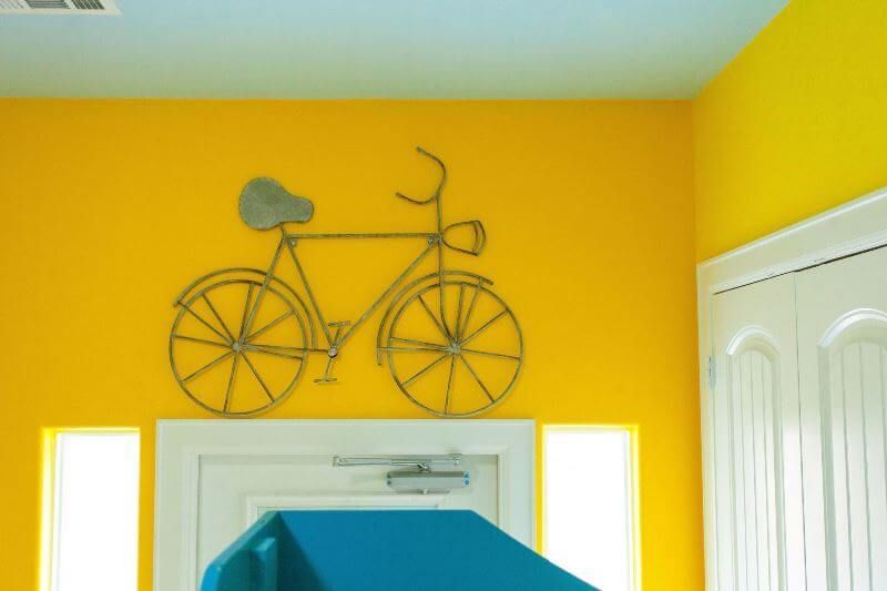 A yellow wall with a bicycle hanging on it