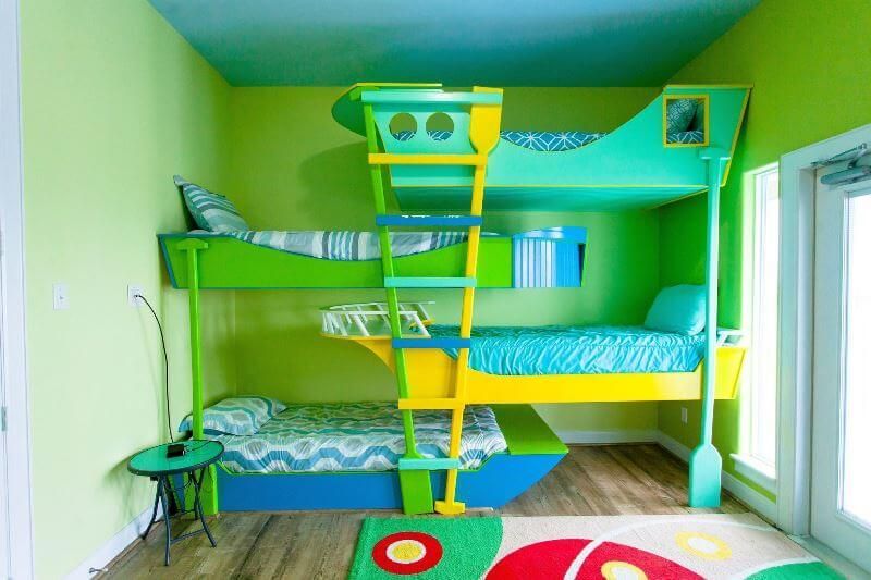 A colorful bunk bed in a room with green walls and a blue ceiling.
