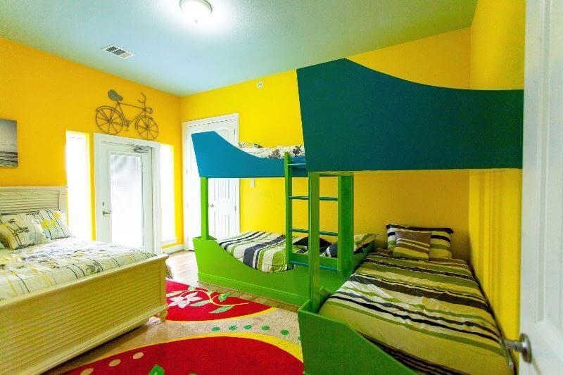 A bedroom with bunk beds , a bed , and a bicycle on the wall.