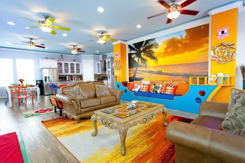 A living room with a couch , chair , coffee table and ceiling fan.