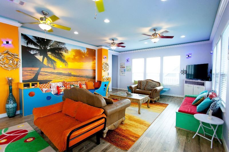 A living room with colorful furniture and a ceiling fan.