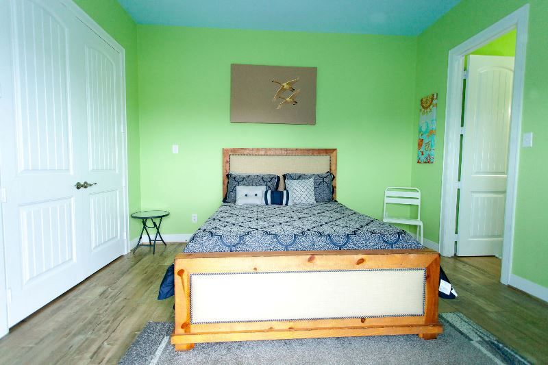 A bedroom with green walls and a wooden bed
