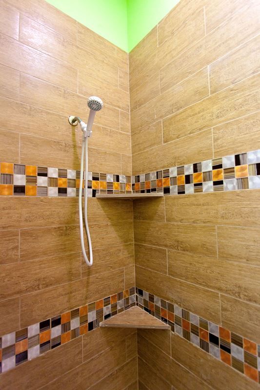 A shower with a corner shelf and a shower head.