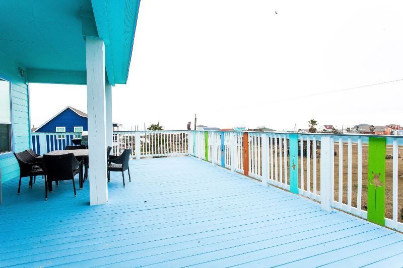 A blue deck with a white railing and a table and chairs on it.