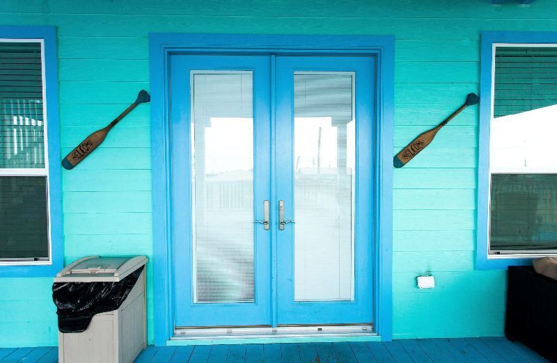 A blue house with a trash can in front of it.
