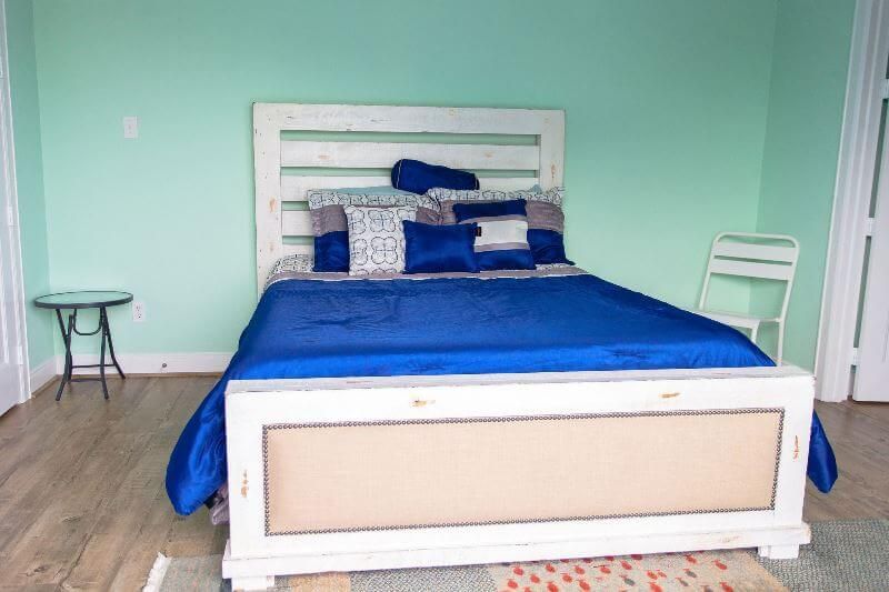 A bedroom with a blue bed and a white headboard