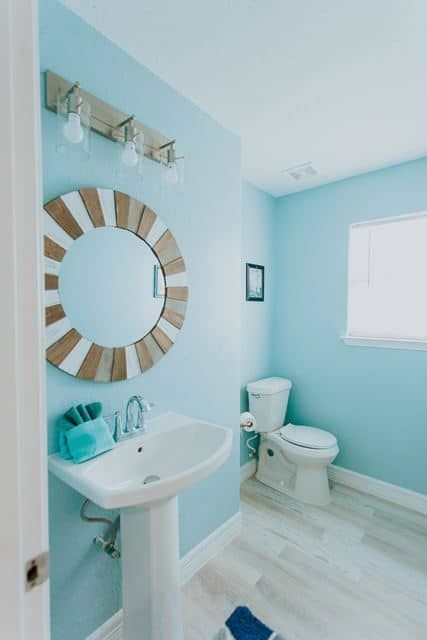 A bathroom with blue walls and a sink and toilet