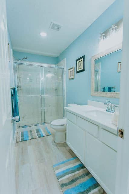 A bathroom with a toilet , sink , mirror and shower.