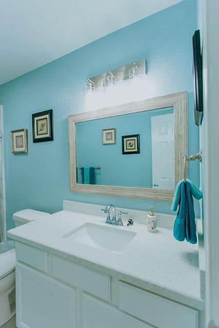 A bathroom with blue walls and a large mirror