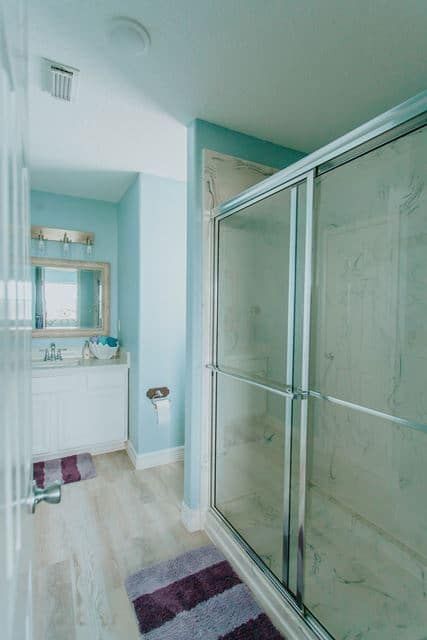 A bathroom with a walk in shower , sink and mirror.