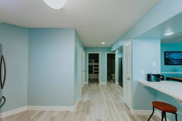 A hallway in a house with blue walls and a wooden floor.