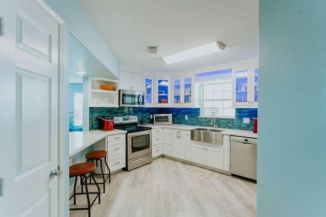 A kitchen with white cabinets , stainless steel appliances , a sink , and a stove.