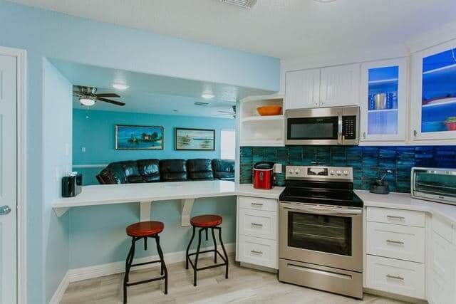 A kitchen with a stove , microwave , and stools.