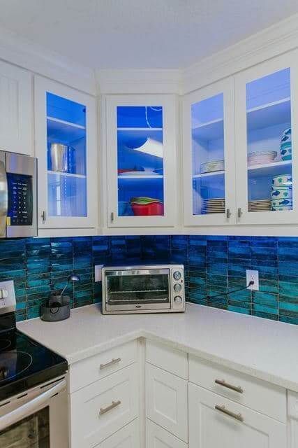 A kitchen with white cabinets , a microwave , and a toaster oven.
