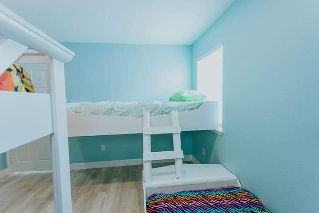 A bunk bed with a ladder in a room with blue walls.