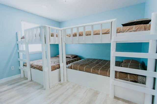 A bedroom with three bunk beds and blue walls.
