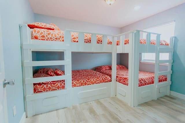 A bedroom with three bunk beds and a window.