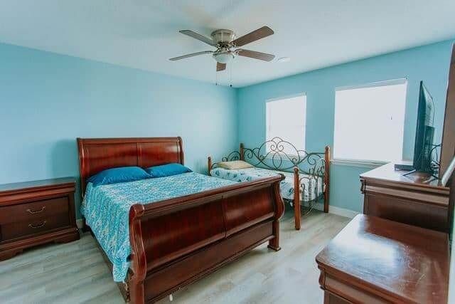 A bedroom with two beds , a ceiling fan and a television.