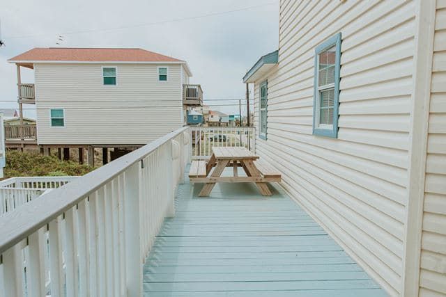 There is a picnic table on the deck of a house.