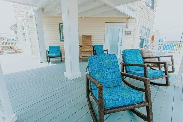There are two rocking chairs on the porch of a house.