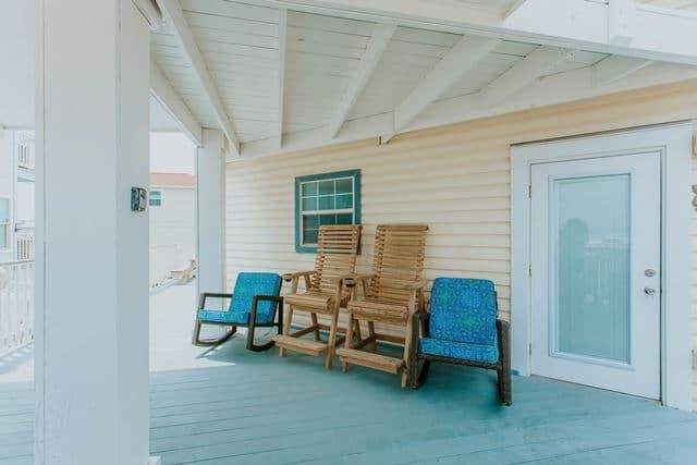 There are two rocking chairs on the porch of a house.
