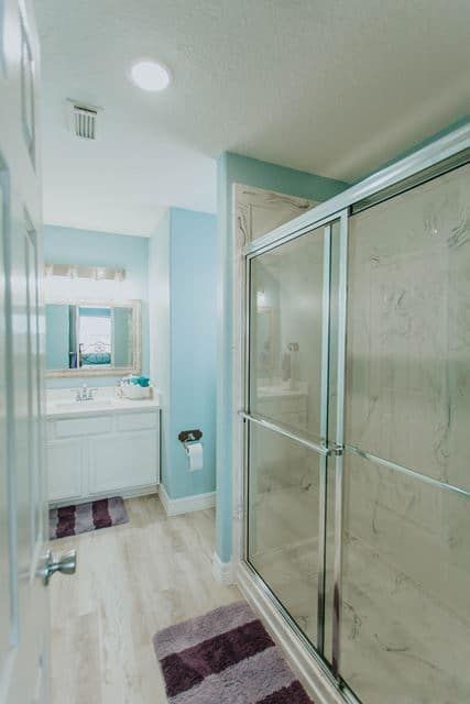 A bathroom with a walk in shower , sink and mirror.