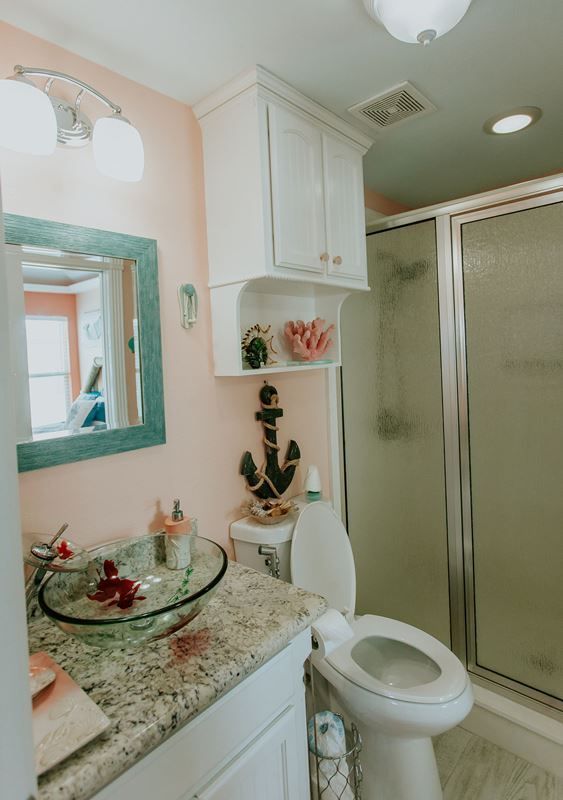 A bathroom with a toilet , sink , mirror and shower.