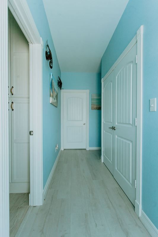 A long hallway with blue walls and white doors