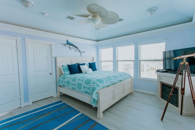 A bedroom with a king size bed , television , fireplace and ceiling fan.