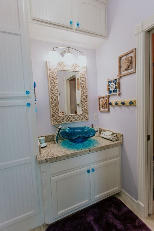 A bathroom with a sink , mirror , and purple rug.