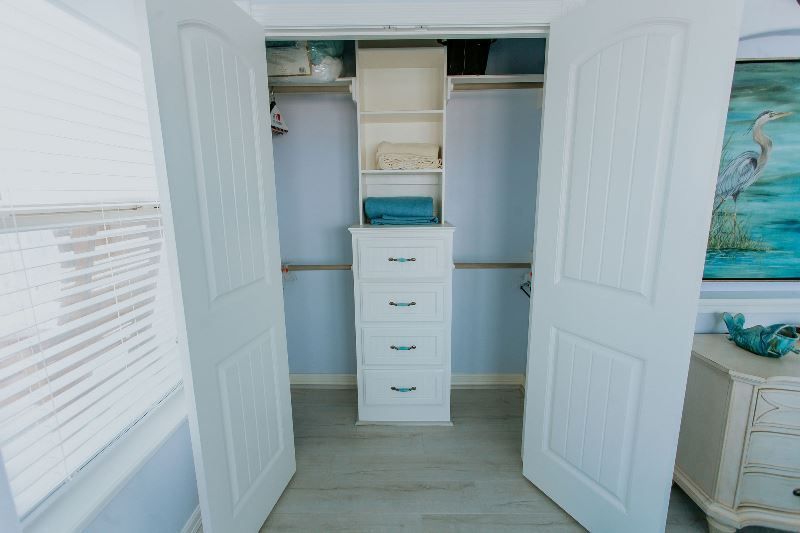 A closet with drawers and shelves in a bedroom with the doors open.