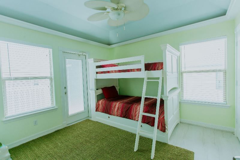 A bedroom with a bunk bed and a ceiling fan.