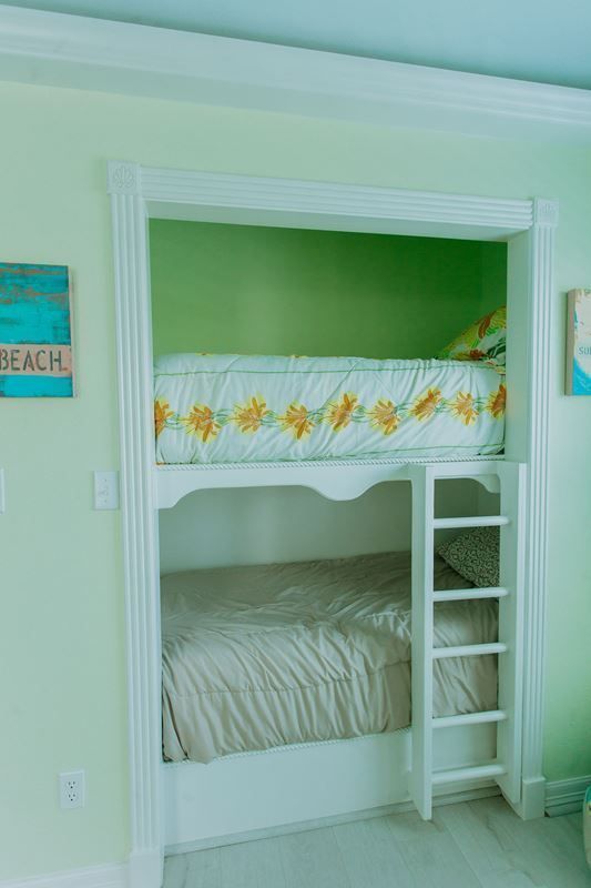 A bunk bed in a closet with a ladder.