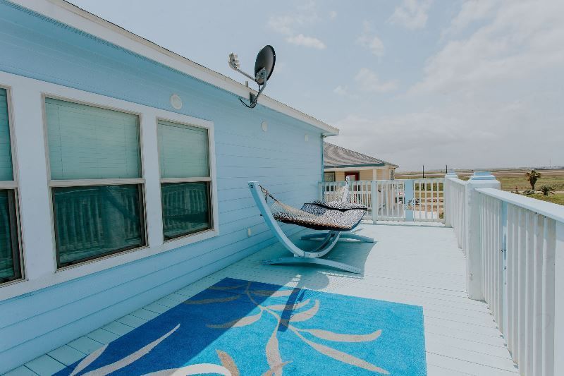 There is a hammock on the deck of a house.