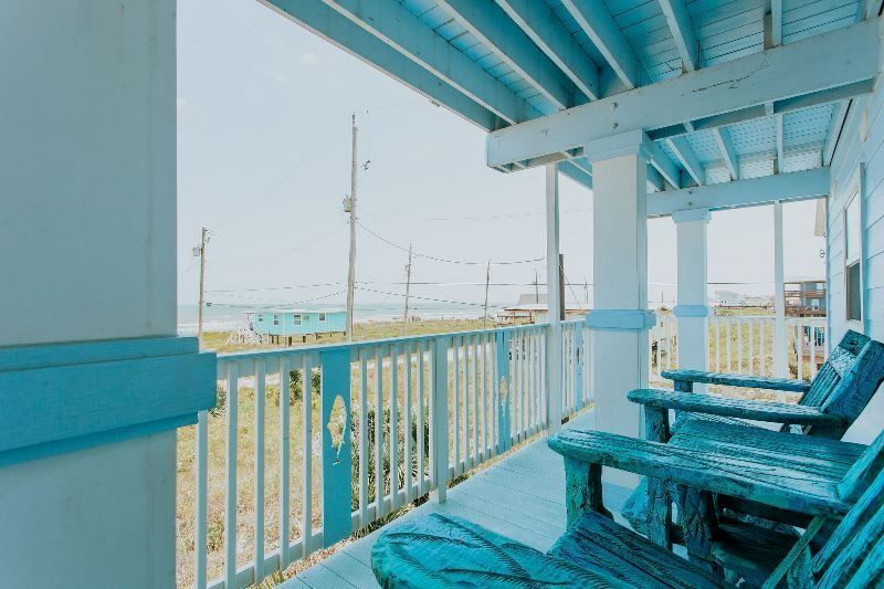 A balcony with blue chairs and a view of the ocean.