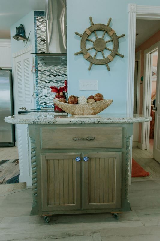 A wooden cabinet with a steering wheel on the wall above it in a kitchen.