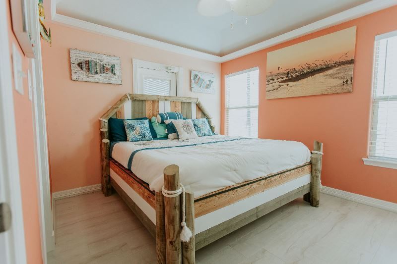 A bedroom with a king size bed and pink walls.